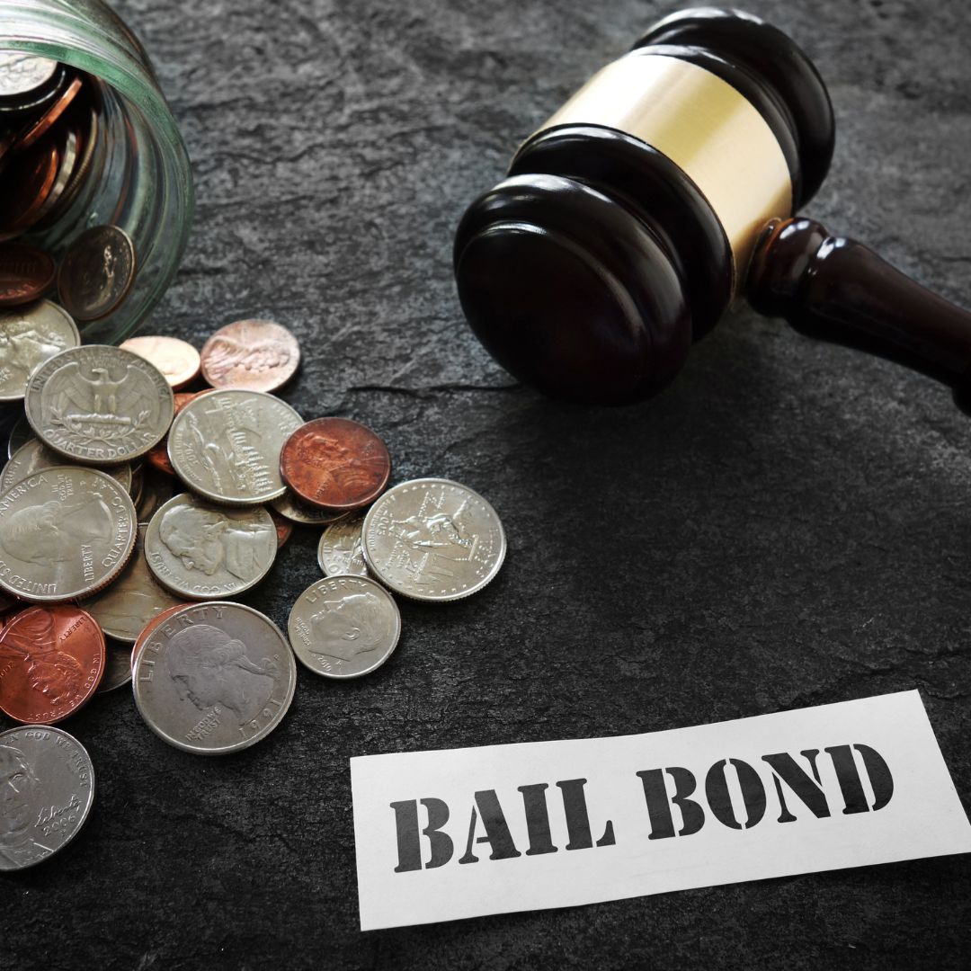 Gavel next to a piece of paper that says "Bail Bond" and some coins spilling out of a jar next to it. 